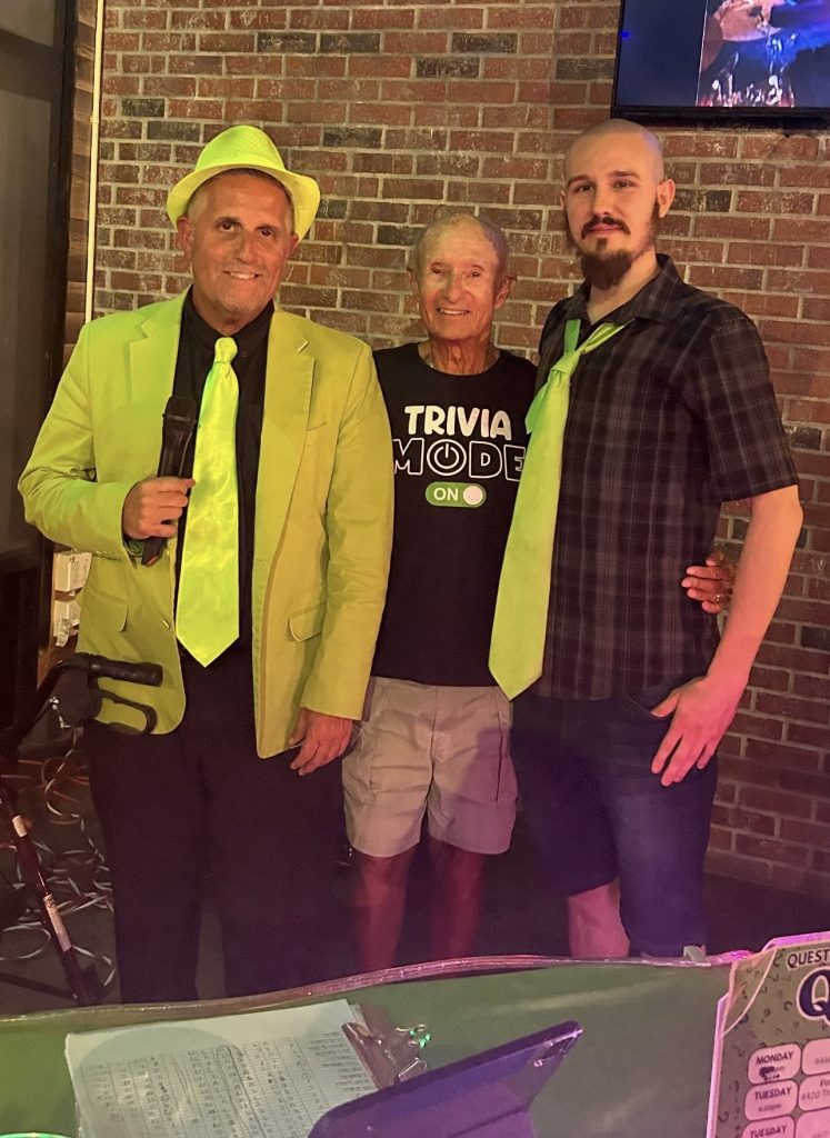 Question Maahk Trivia owner Mark Marino standing with several individuals from trivia night.