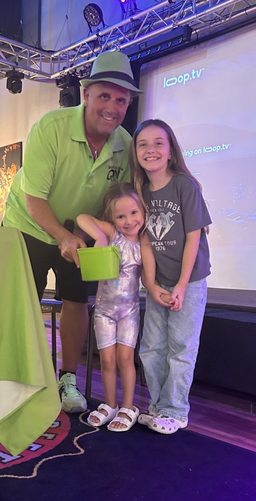 Mark Marino, host and owner of Question Maahk Trivia, standing with two young participants at one of his weekly events.