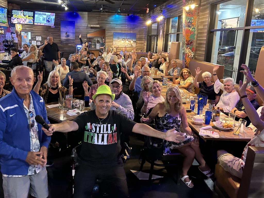 Question Maahk Trivia owner Mark Marino standing in front of a crowd at one of his restaurant locations.
